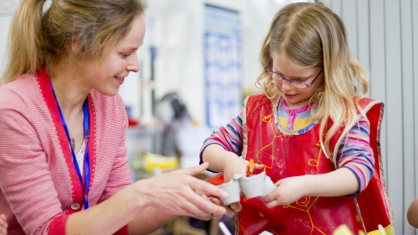 Teacher helping pupil with a primary DT project 